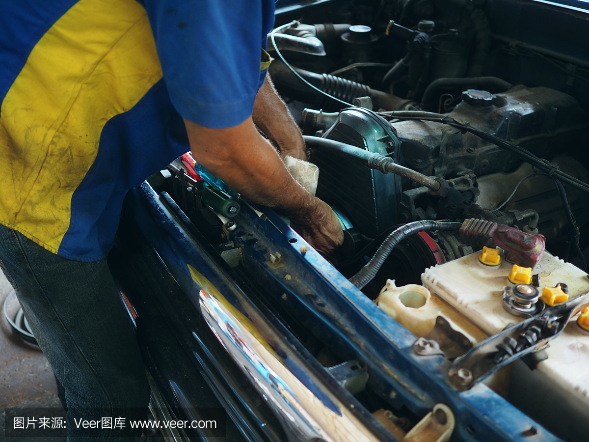 穿着制服的技工在车库里修理汽车。汽车修理服务。